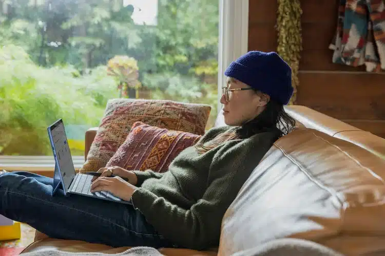 A person relaxes on a couch with a laptop.