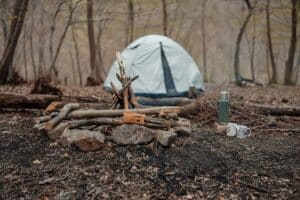 A tent in the woods near a pile of logs