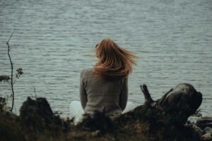 A woman sitting on the shore of a lake