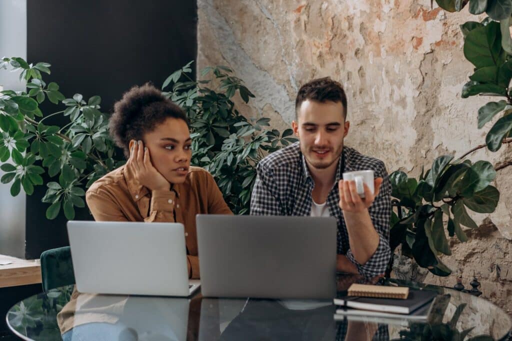 Two startup founders collaborating in an office while managing business stress and communication challenges.