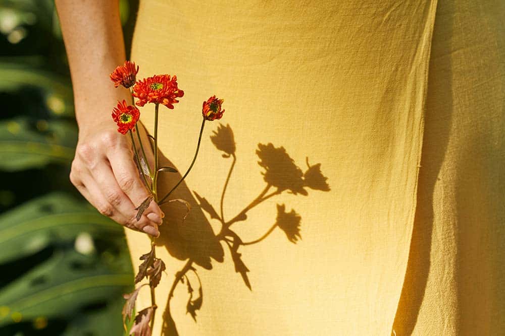 a-woman-in-a-yellow-dress-holding-red-flowers