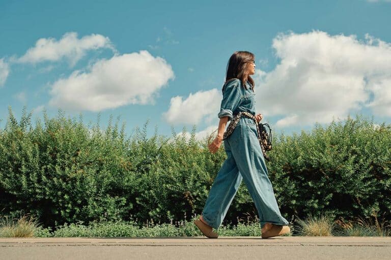 Stylish woman in denim and scarf walking outdoors.