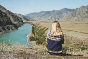 young blonde woman in nordic sweater sitting on background