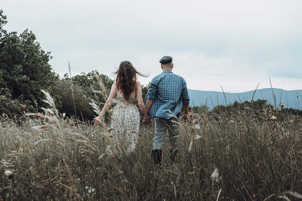 Man and Woman Walking on a Grass Field